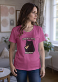 Woman wearing a pink t-shirt featuring a whimsical cat graphic and the text Give me a bite Meoww.